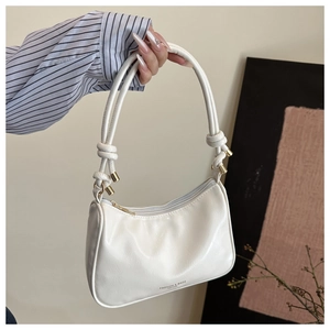 Détail du sac sous le bras en simili cuir blanc avec poignée nouée et accents dorés