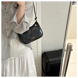 Detail of a minimalist black glossy leather baguette bag with golden logo and slim strap