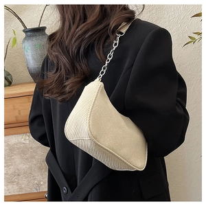 Detail of beige corduroy crescent shoulder bag featuring silver metal chain strap for women