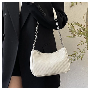 Detail of white woven crescent bag with silver chain strap on black blazer