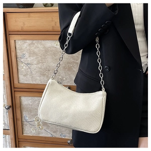 Detail of a creamy white half-moon shoulder bag with chain strap worn by a model in black