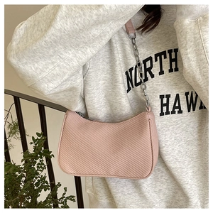 Detail of pink hobo bag featuring woven texture and chain strap worn by model