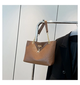 Detail of dark brown woven texture shoulder bag with gold chain and deer charm