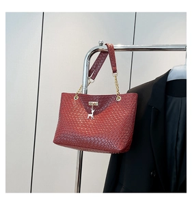 Detail of red woven texture tote bag with gold chain strap and deer metal pendant