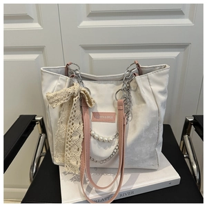 Detail of canvas tote bag with lace bow, faux pearls and silver metal chain accessory