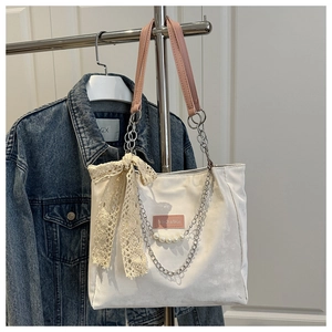 Detail of white tote bag with pink handles, silver chain, pearls and lace bow detail
