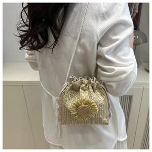 Detail of woven straw bucket bag with sunflower decor and white drawstring shoulder strap