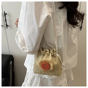 Detail of straw woven bucket bag featuring sunflower decor and drawstring closure