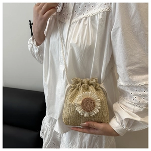 Detailed shot of a woven straw bucket bag featuring a white sunflower and drawstring closure