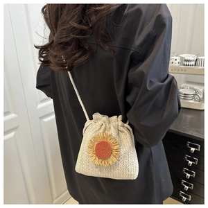 Detailed view of beige woven bucket bag with sunflower applique on model shoulder