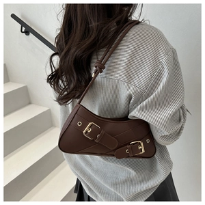 Detail of dark brown leather underarm bag with gold buckles and cross strap design