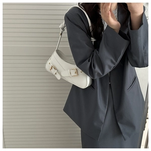 Close-up of white shoulder bag with decorative straps and thick rope handle detail