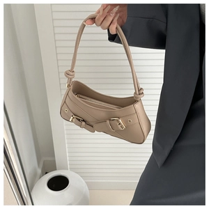 Detail of beige leather underarm bag featuring decorative straps and gold buckles