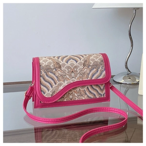 Detail of rose red Chinese style crossbody bag with silk brocade patterns and gold hardware
