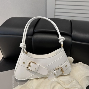 White underarm handbag with gold buckle straps and knotted handle on dark background