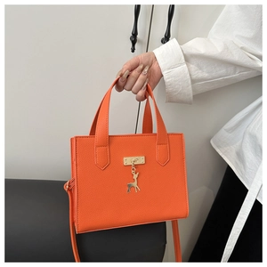 Détail du sac à main orange en similicuir avec serrure dorée et pendentif de cerf