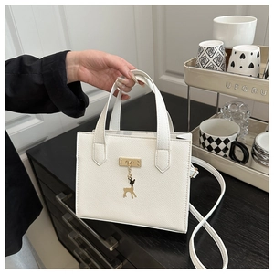 Gros plan du sac à main blanc à motif litchi avec pendentif cerf doré et sangle