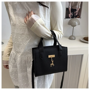 Détail d'un sac noir avec pendentif cerf doré dans un décor intérieur minimaliste