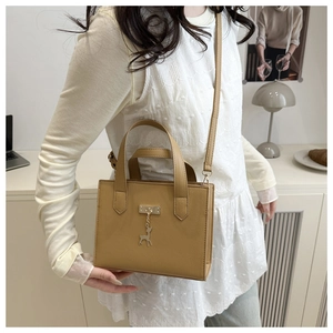 Détail du cuir grainé marron et du pendentif cerf en métal sur un sac à main rectangulaire