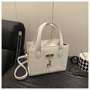 Détails du cuir blanc à texture litchi et du pendentif cerf doré sur le petit sac