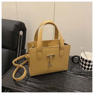 Détail du sac en cuir jaune moutarde avec pendentif cerf doré et boucle métallique