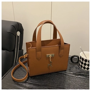 Détail du sac à main marron avec motif litchi, pendentif cerf doré et accessoires
