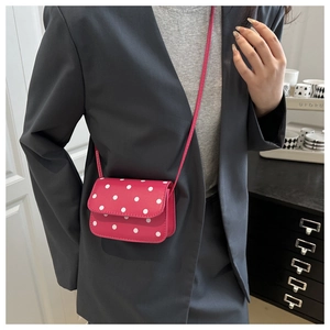 Polka dot mini crossbody bag in magenta with a classic flap design on a model