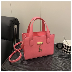 Vue détaillée du sac rose en cuir synthétique avec pendentif cerf doré et fermoir en métal