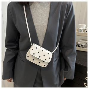Mini sac bandoulière à pois porté avec un blazer gris pour un style chic et décontracté
