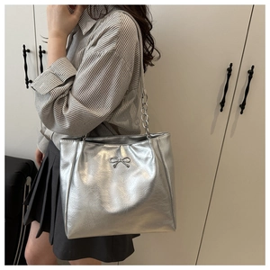 Detail der silbernen Metallic-Tragetasche mit Knitteroptik und Schleifendekor