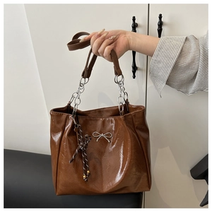Detailansicht der braunen Tragetasche mit silberner Schleife und schicker Kette