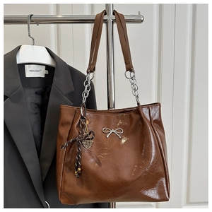Detail of brown oil wax leather tote bag with silver bow and tennis racket pendant