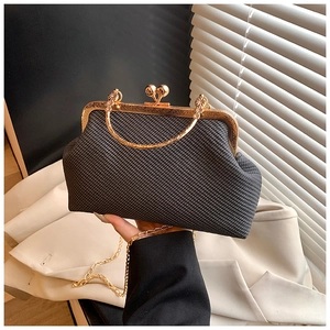 Close-up of vintage black shell bag with woven texture and gold metal clasp