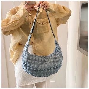 Detail of light blue popcorn texture fabric on a stylish crescent shoulder bag with metal buckle