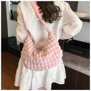 Detail of light pink pleated hobo bag texture and wide strap shown on shoulder