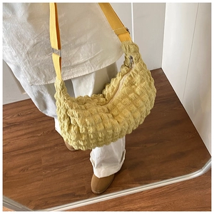 Detailed texture of yellow cloud bag featuring unique bubble pleated fabric and strap