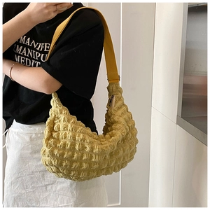 Detail of yellow pleated cloud bag featuring textured bubble fabric and wide shoulder strap
