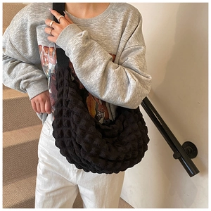 Detail of black puff cloud crossbody bag with popcorn texture hobo design on model