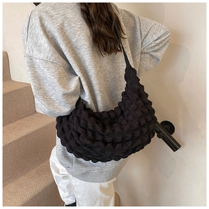 Detailed view of black bubble texture fabric shoulder bag worn by model on stairs