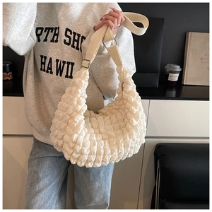 Detail of creamy white popcorn bag texture with a wide canvas shoulder strap and silver buckle