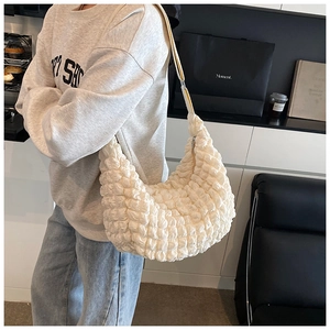 Detail of the soft bubble pleated texture on an off-white half-moon cloud shoulder bag
