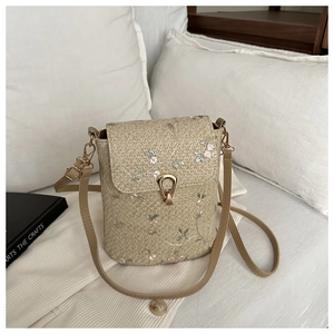 Dettaglio del ricamo floreale su borsa a secchiello beige con chiusura a U dorata