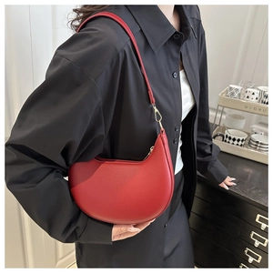 Detailed view of red crescent shoulder bag with lychee texture and gold metal accents