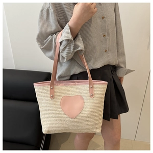 Détail du sac cabas en paille beige avec patch coeur rose et anses en cuir