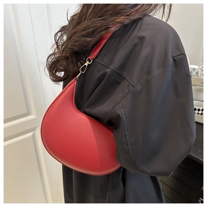 Close-up of red crescent moon shoulder bag with lychee grain leather on black outfit
