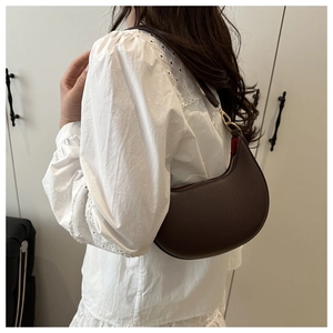 Detail of dark brown crescent underarm bag with lychee texture and gold hardware
