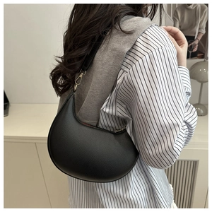 Close-up of black lychee grain leather crescent bag worn by model in soft natural light