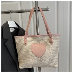 Détail du sac cabas en paille tressée avec patch cœur rose et anses en cuir robustes