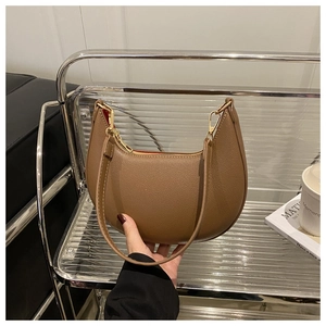 Coffee brown leather crescent bag with gold hardware shown in a hand-held lifestyle setting
