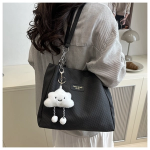 Detail of black corduroy tote bag texture with cute cloud charm in a cozy home setting